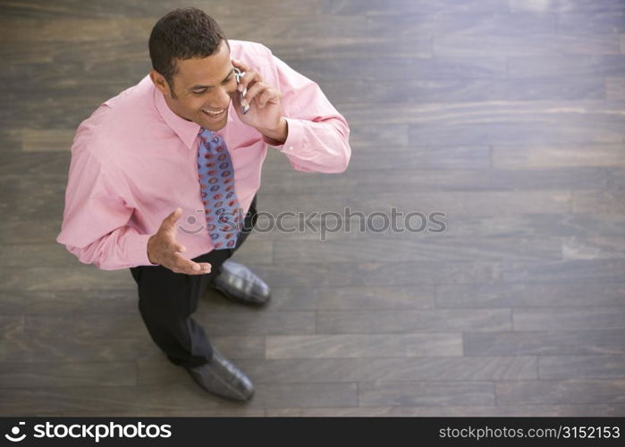 Businessman standing indoors using cellular phone smiling