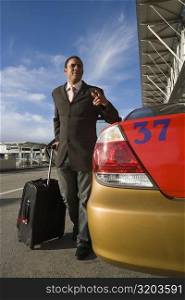 Businessman standing near a taxi with holding his luggage and gesturing