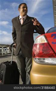 Businessman standing near a taxi with holding his luggage and smiling