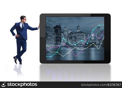 Businessman standing next to tablet computer on white background