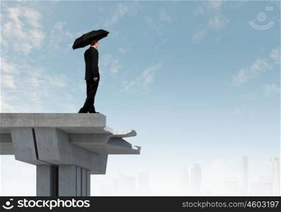 Businessman standing on bridge. Young businessman with umbrella standing on bridge