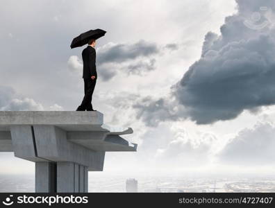 Businessman standing on bridge. Young businessman with umbrella standing on bridge