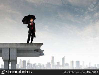 Businessman standing on bridge. Young businessman with umbrella standing on bridge