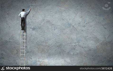 businessman standing on ladder drawing diagrams and graphs