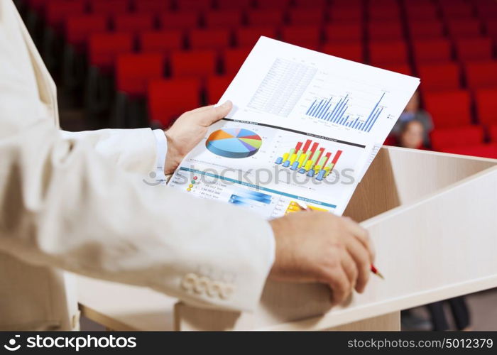 Businessman standing on stage and reporting for audience