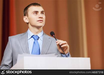 Businessman standing on stage and reporting for audience. Speaker at stage