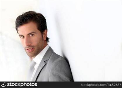 Businessman standing on white wall- profile view