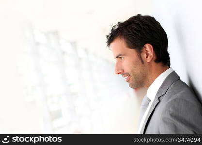 Businessman standing on white wall- profile view