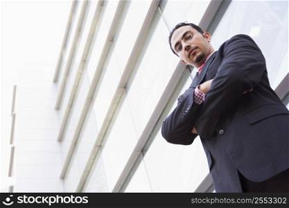 Businessman standing outdoors by building (high key/selective focus)