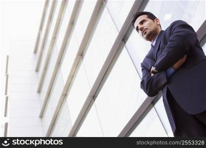 Businessman standing outdoors by building (high key/selective focus)