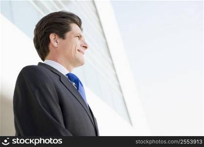 Businessman standing outdoors by building smiling