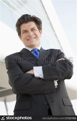 Businessman standing outdoors by building smiling