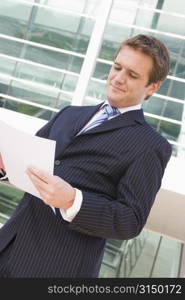 Businessman standing outdoors looking at paperwork