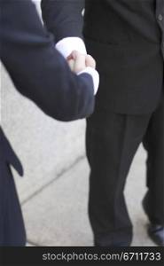 Businessman standing outside and gives another business woman a handshake
