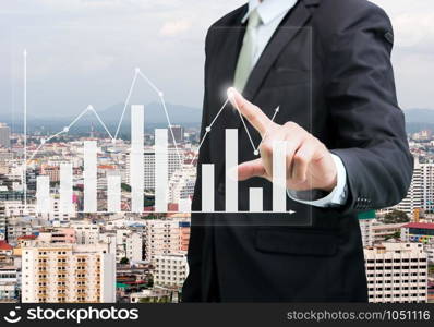 Businessman standing posture hand touch graph finance on City background