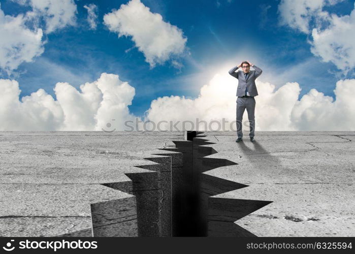 Businessman standing scared next to cliff