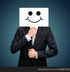 Businessman standing white paper happy smile face holding front of head on dark background