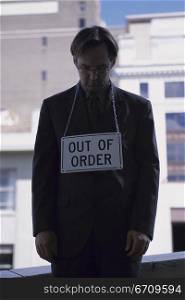 Businessman standing with an out of order sign around his neck