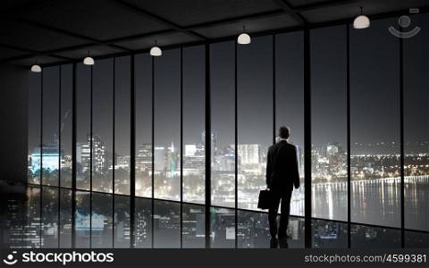Businessman standing with back and looking in office window. Office life