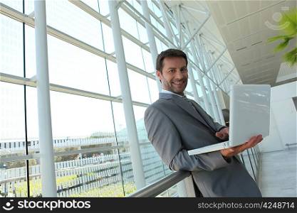 Businessman standing with laptop.