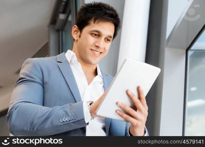 Businessman standing with tablet smiling at camera. Success and professionalism in person