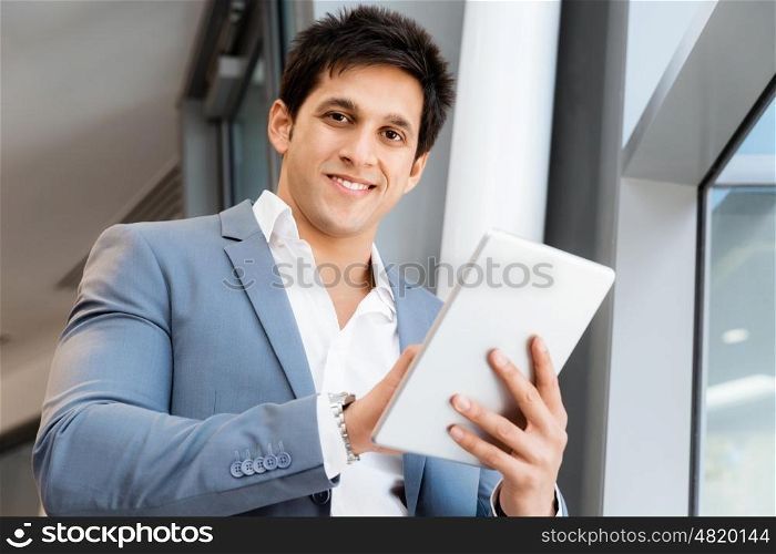 Businessman standing with tablet smiling at camera. Success and professionalism in person