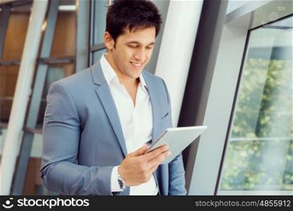 Businessman standing with tablet smiling at camera. Success and professionalism in person