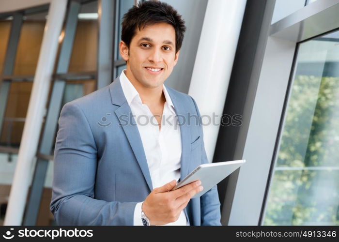 Businessman standing with tablet smiling at camera. Success and professionalism in person