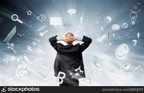 Businessman stands back and looks at flying objects. Businessman and flying puzzle