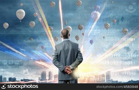 Businessman stands back and looks at flying objects. Making decision