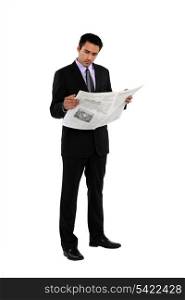 Businessman stood reading the newspaper