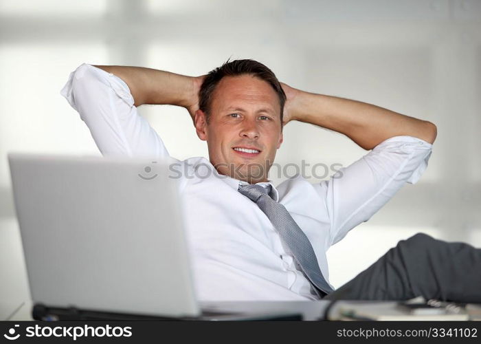 Businessman stretching arms in the office