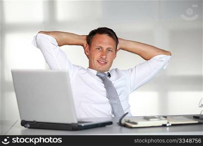 Businessman stretching arms in the office