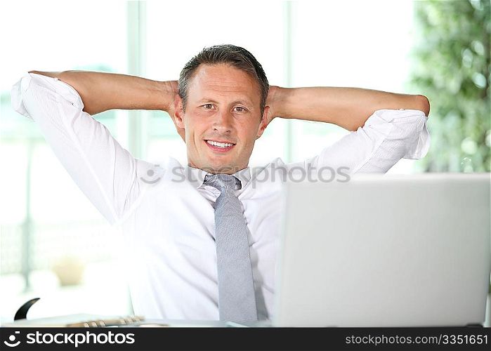 Businessman stretching arms in the office