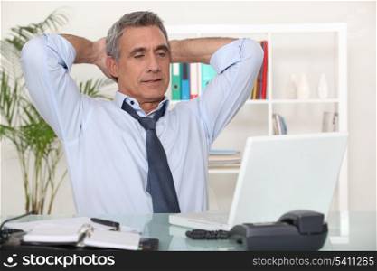 Businessman stretching at his desk
