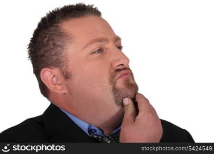 Businessman stroking his beard whilst thinking