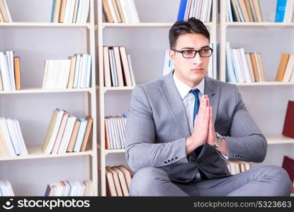 Businessman student in lotus position concentrating in the libr. Businessman student in lotus position concentrating in the library