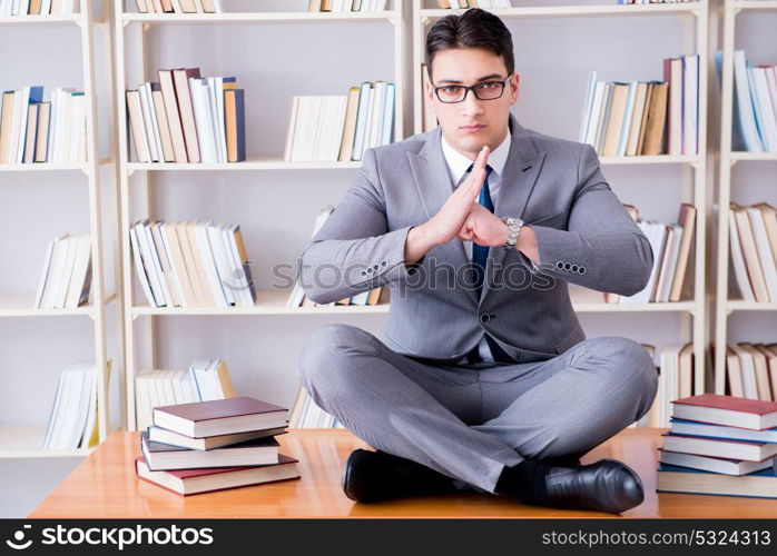 Businessman student in lotus position concentrating in the libr. Businessman student in lotus position concentrating in the library