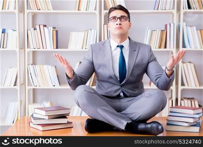 Businessman student in lotus position concentrating in the libr. Businessman student in lotus position concentrating in the library