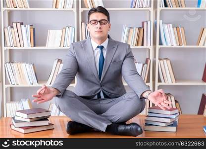 Businessman student in lotus position concentrating in the libr. Businessman student in lotus position concentrating in the library