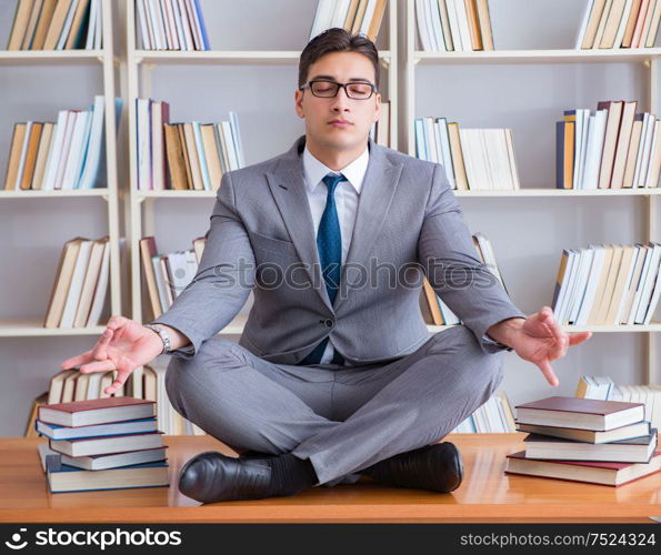 Businessman student in lotus position concentrating in the library. Businessman student in lotus position concentrating in the libr