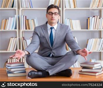 Businessman student in lotus position concentrating in the library. Businessman student in lotus position concentrating in the libr