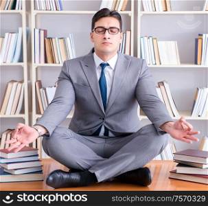 Businessman student in lotus position concentrating in the library. Businessman student in lotus position concentrating in the libr
