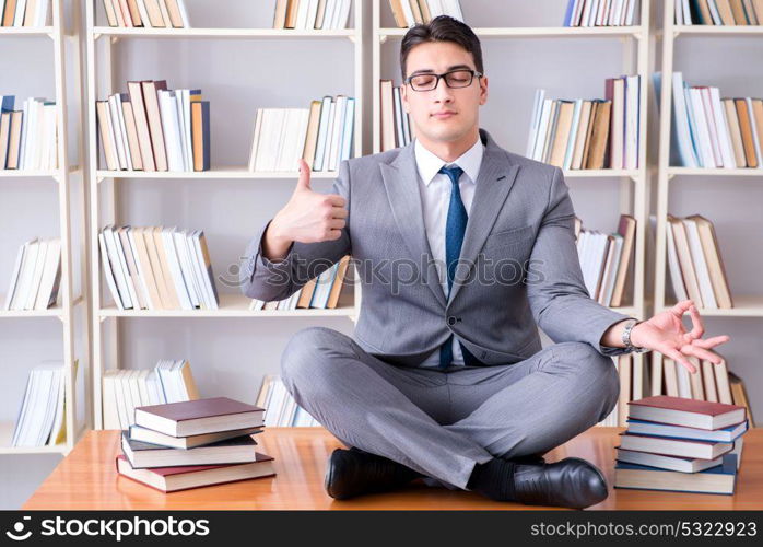 Businessman student in lotus position concentrating meditating . Businessman student in lotus position concentrating meditating in the library