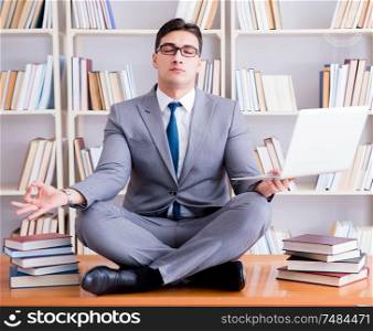 Businessman student in lotus position meditating with a laptop in library. Businessman student in lotus position meditating with a laptop i
