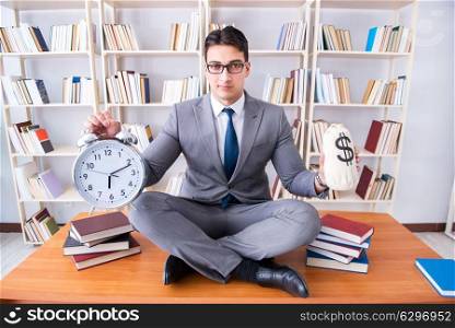 Businessman student in lotus position with an alarm clock and a . Businessman student in lotus position with an alarm clock and a money bag in library