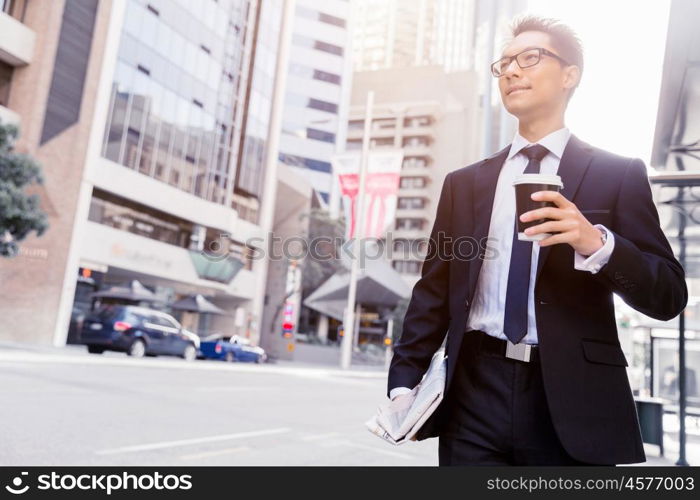 Businessman swalking in street and holding a coffee. Businessman with coffee in a city