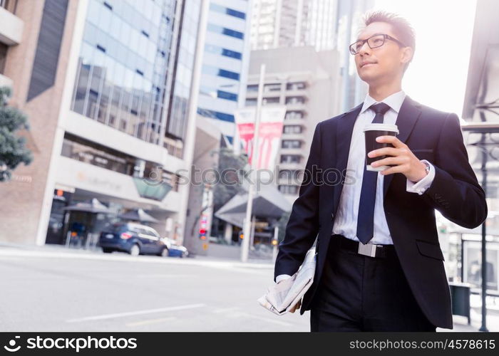 Businessman swalking in street and holding a coffee. Businessman with coffee in a city