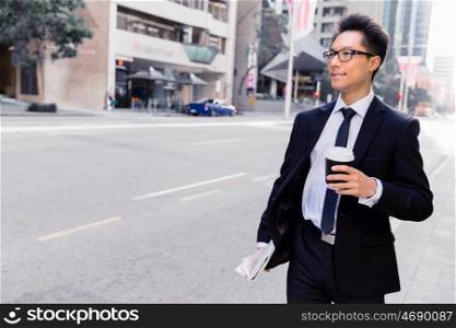 Businessman swalking in street and holding a coffee. Businessman with coffee in a city