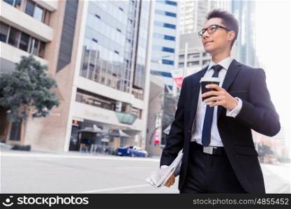 Businessman swalking in street and holding a coffee. Businessman with coffee in a city